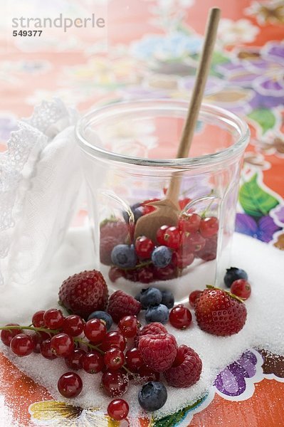 Frische Beeren im Marmeladenglas mit Zucker und Kochlöffel