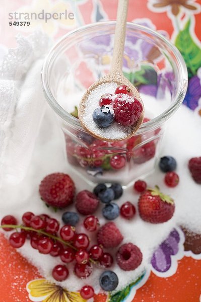 Frische Beeren im Marmeladenglas mit Zucker und Kochlöffel