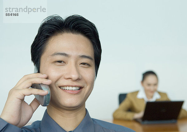 Geschäftsmann am Handy  Kollege im Hintergrund  Porträt