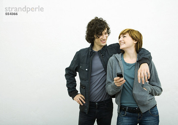 Junges erwachsenes Paar schaut sich an  Mann mit Arm um Frau  Frau hält Handy