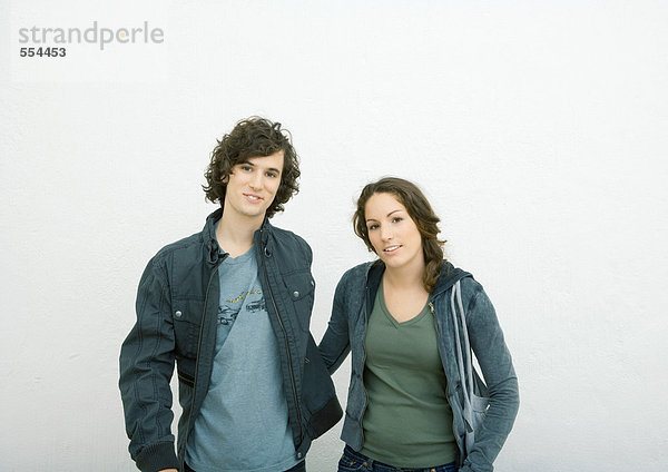 Junges Paar steht nebeneinander  schaut in die Kamera  Portrait  weißer Hintergrund