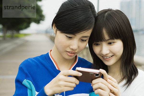 Zwei junge Frauen schauen gemeinsam auf den Bildschirm einer Digitalkamera