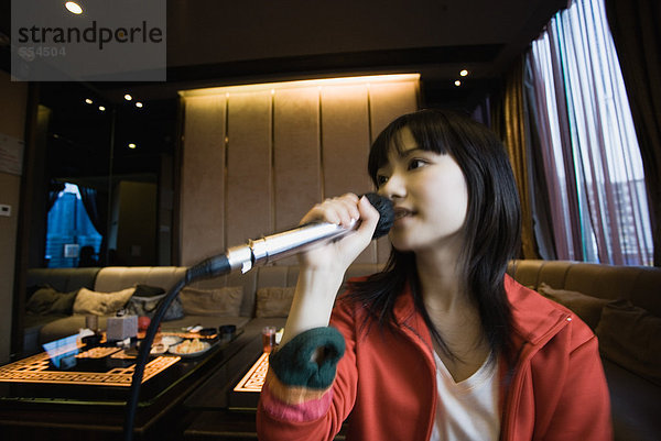 Junge Frau singt Karaoke