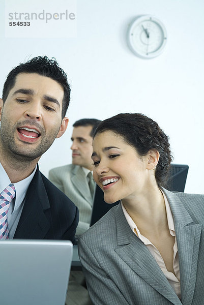 Geschäftsfreunde  die am Computer arbeiten  sprechende Männer und lächelnde Frauen
