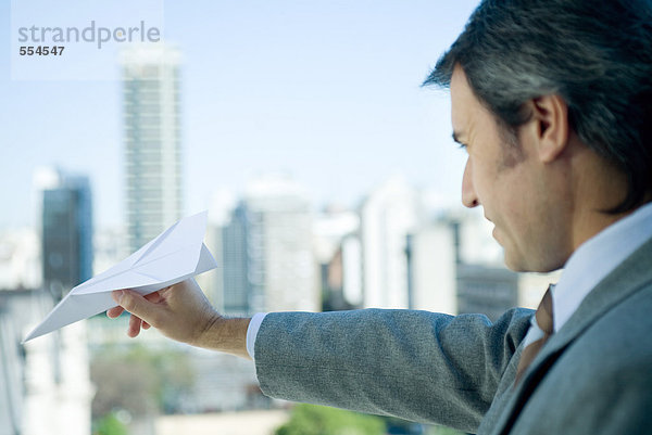 Geschäftsmann mit Papierflugzeug  Skyline im Hintergrund