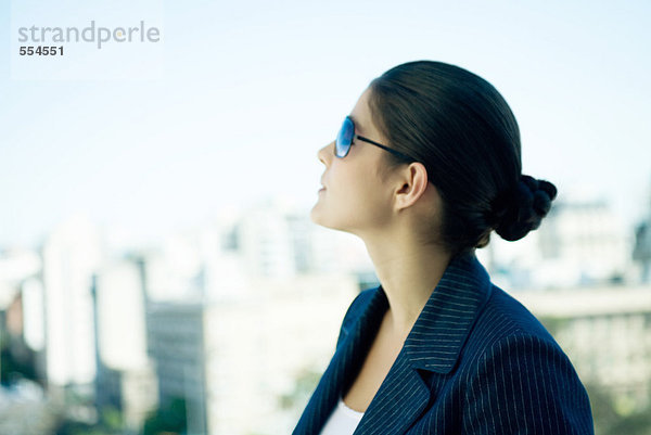 Frau mit Sonnenbrille  Blick nach oben  Skyline im Hintergrund  Profil