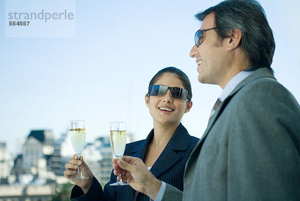 Geschäftspartner mit Champagnergläsern  Skyline im Hintergrund