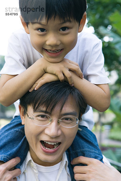 Junge reitet auf Vaters Schultern  Frontansicht  lächelt in die Kamera