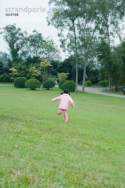 Kleines Mädchen läuft über Gras  Rückansicht