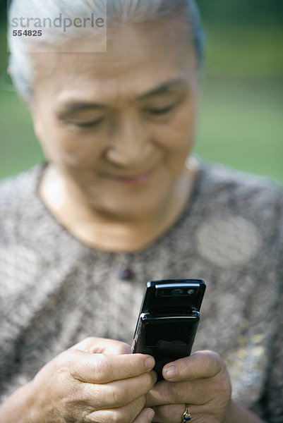 Seniorenfrau wählt Handy