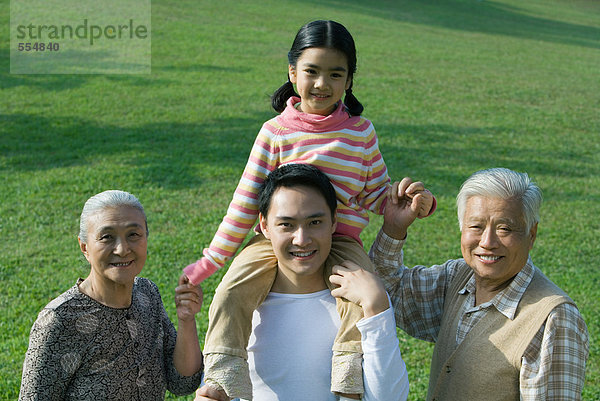 Drei Generationen Familie  Mädchen auf Vaters Schultern sitzend  Großelternhände haltend  Porträt