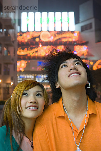 Teenager-Paar schaut nach oben  Lichter im Hintergrund