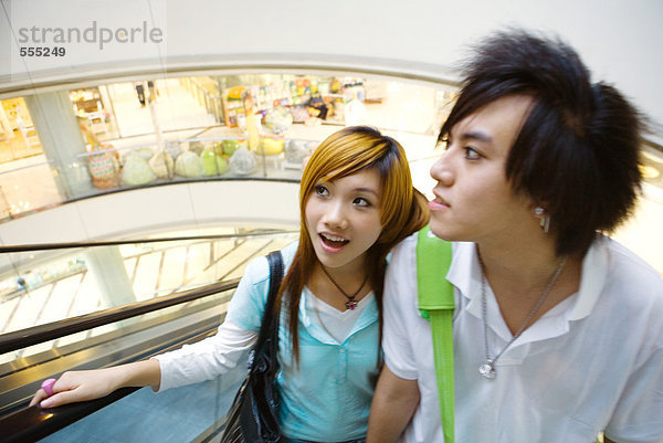Teenager-Paar auf Rolltreppe im Einkaufszentrum