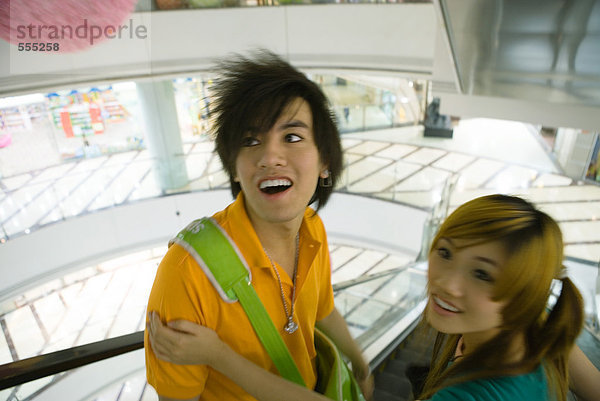 Teenager-Paar auf einer Rolltreppe im Einkaufszentrum  Blick in den hohen Winkel