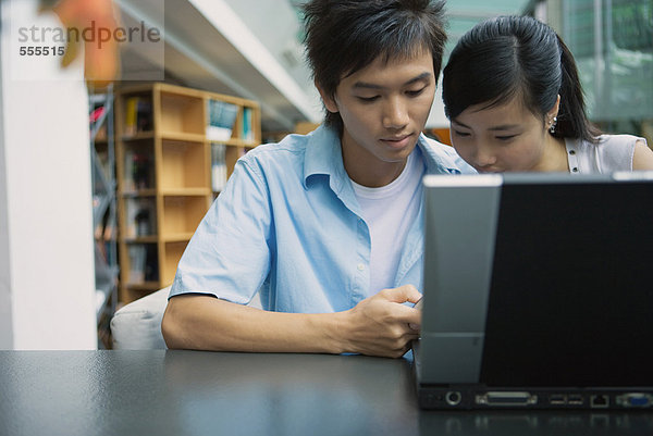 Junges Paar mit Laptop in der Bibliothek