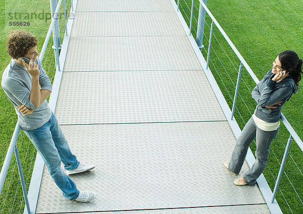 Teenager-Paar stehend von Angesicht zu Angesicht auf dem Gehweg  mit dem Handy  volle Länge  hohe Blickwinkel