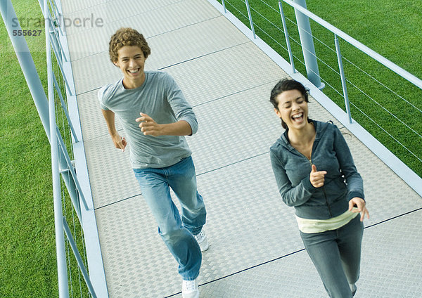 Teenager-Paar läuft auf dem Gehweg  lachend  hohe Blickwinkel