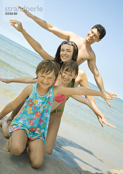 Familie am Strand aufgereiht mit ausgestreckten Armen
