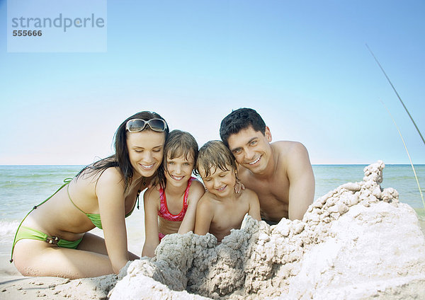 Familie sitzt am Strand in der Nähe von Sandhaufen  Portrait