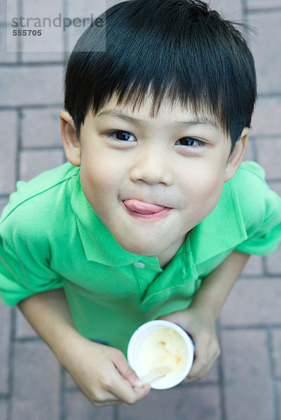 Junge isst Eiscreme  leckt die Lippen.