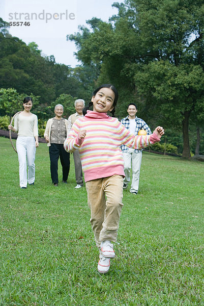 Mädchen tanzen  während Eltern und Großeltern im Hintergrund zuschauen.
