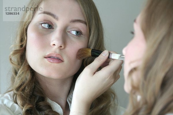 Reflexion der junge Frau Anwendung Rouge mit einem Pinsel in Spiegel mund