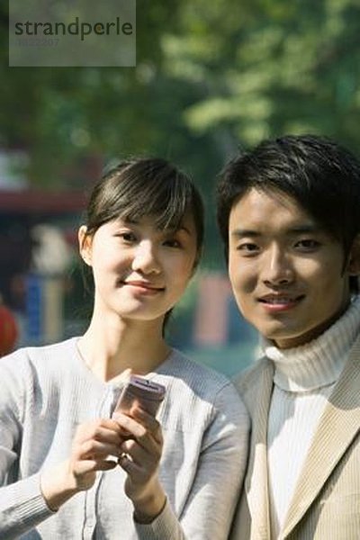 Junges Paar mit Handy  lächelnd in die Kamera  Portrait