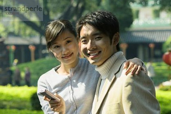 Junges Paar mit Handy  lächelnd in die Kamera  Portrait