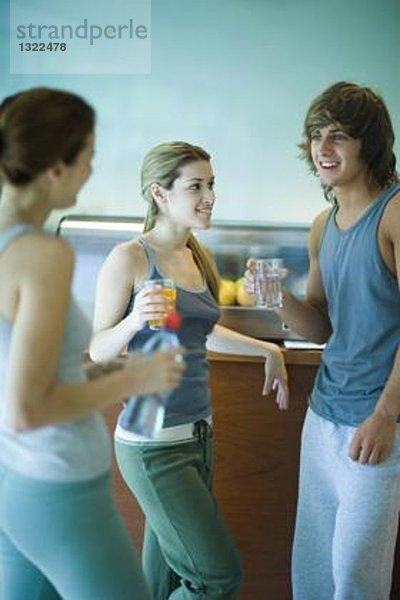 Junge Erwachsene in Sportkleidung  Stehen in der Cafeteria  gesunder Snack und Plaudern