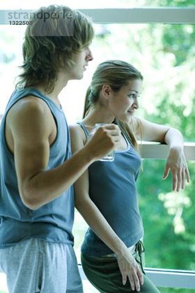Junges Paar in Trainingskleidung am Fenster stehend
