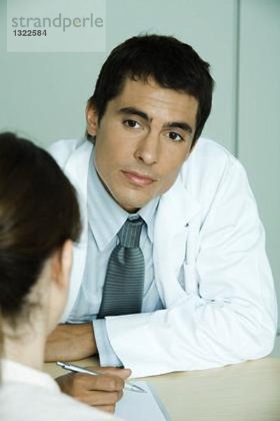 Arzt sitzt gegenüber der Patientin