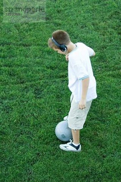 Junge stehend mit Ball  Kopfhörer tragend