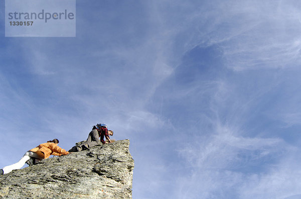 Junges Paar beim Klettern auf den Berggipfel  Tiefblick