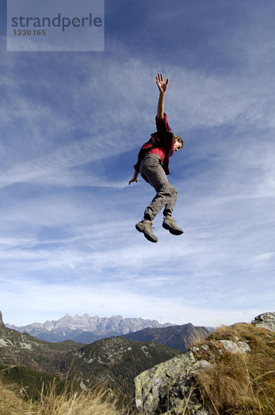 Mann springt über Berge  Arme ausstrecken  Seitenansicht