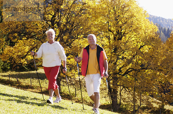 Deutschland  Bayern  Seniorenpaar Nordic Walking  lächelnd