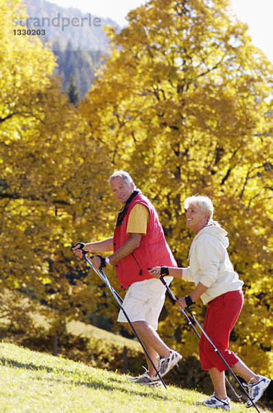 Seniorenpaar Nordic Walking  lächelnd  Seitenansicht