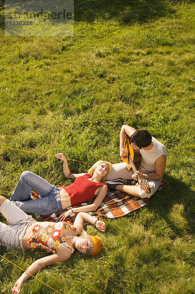 Drei junge Leute beim Picknick  Mann beim Gitarrespielen