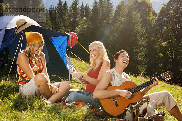 Drei junge Leute beim Picknick  Mann beim Gitarrespielen
