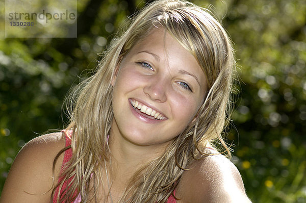 Teenagermädchen (16-17) auf der Wiese sitzend  lächelnd  Nahaufnahme  Porträt