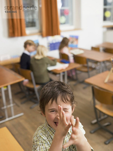 Kinder (4-7) im Klassenzimmer  Fokus auf die Gestik des Jungen im Vordergrund  erhöhte Ansicht