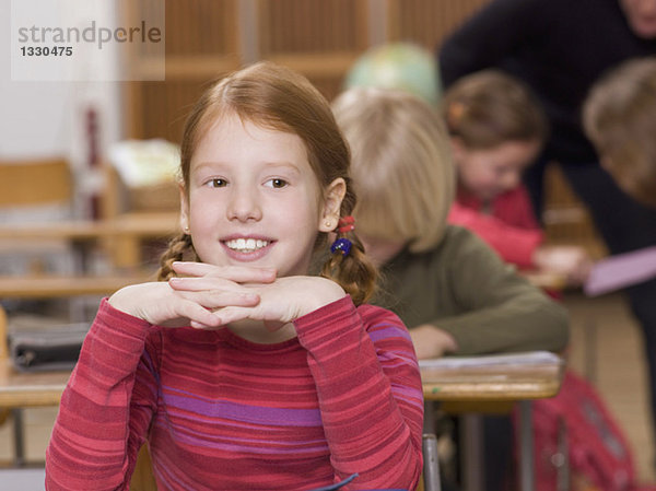 Mädchen (4-7) im Klassenzimmer  lächelnd  Kopf an den Händen  Nahaufnahme