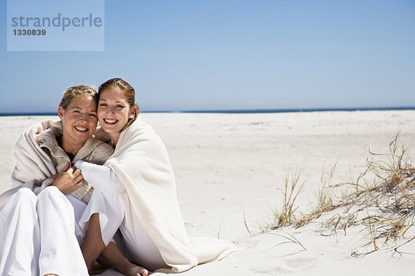 Mutter und Tochter am Strand sitzend