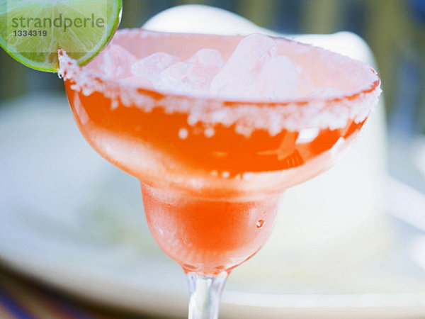 Limetten-Cocktail in orangefarbenem Glas