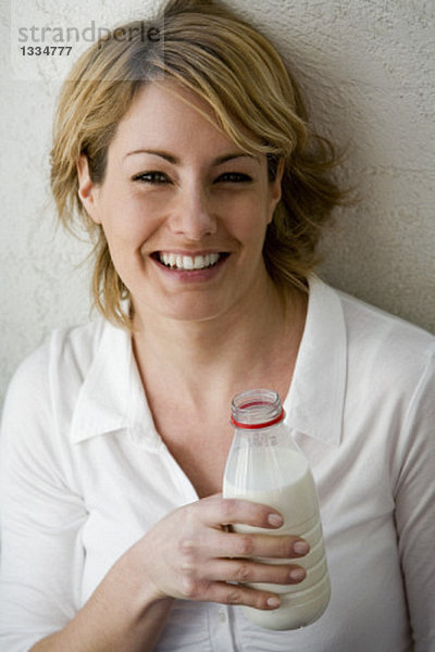 Junge Frau hält eine Flasche Milch in der Hand