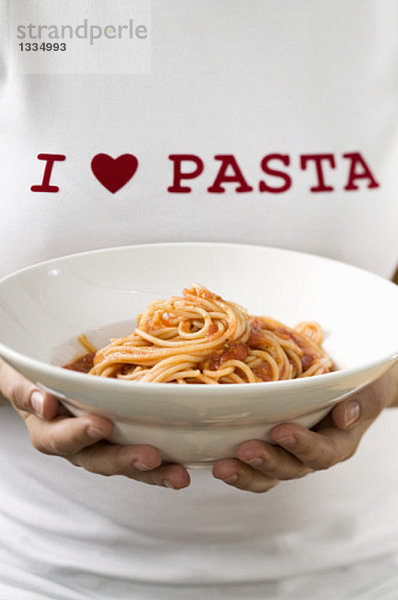 Frau hält Pastateller mit Spaghetti & Tomatensauce