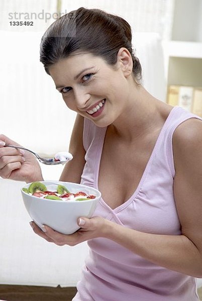 Frau isst Joghurt mit Kiwi und Erdbeeren