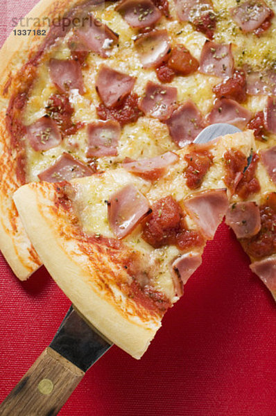 Pizza mit Schinken  Tomaten und Käse mit Stück auf Heber