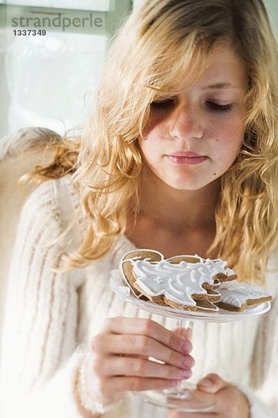 Blondes Mädchen hält Glasschale mit verschiedenen Lebkuchen