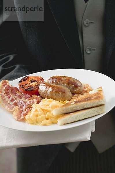 Butler serviert englisches Frühstück auf Teller