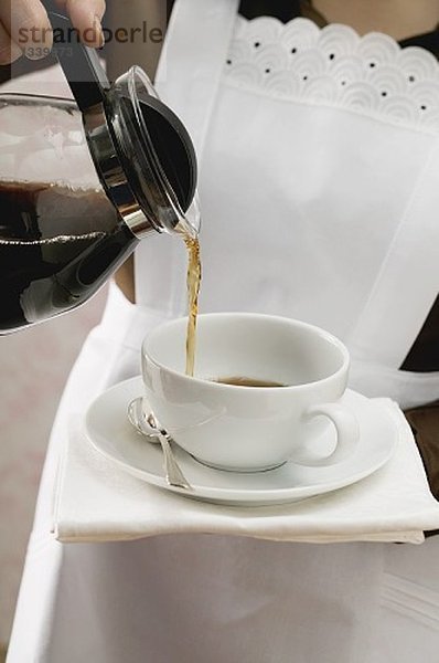 Zimmermädchen giesst Kaffee in Tasse